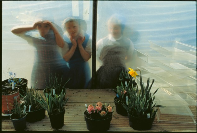 Hutterite children peer into the window of a greenhouse at Deer Spring where the denomination lives without modern appliances, 1991. PHOTOGRAPH BY JOEL SARTORE, NATIONAL GEOGRAPHIC