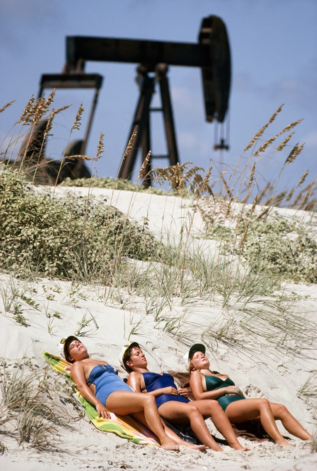 Women bask in the sun beside oil pumps, Padre Island, Texas. April 1980. PHOTOGRAPH BY GORDON GAHAN, NATIONAL GEOGRAPHIC CREATIVE