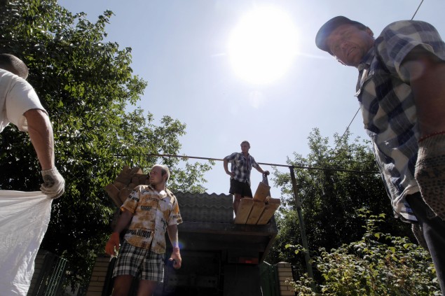 Muži pomáhajú opravovať dom poškodený ostreľovaním v Toninke.