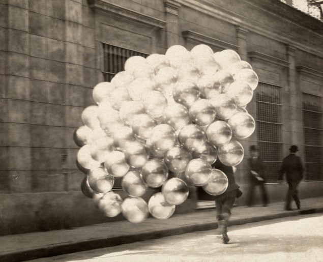 A balloon vendor runs across a road with a trailing mass of balloons in Buenos Aires, November 1921. PHOTOGRAPH BY NEWTON W. GULICK, NATIONAL GEOGRAPHIC