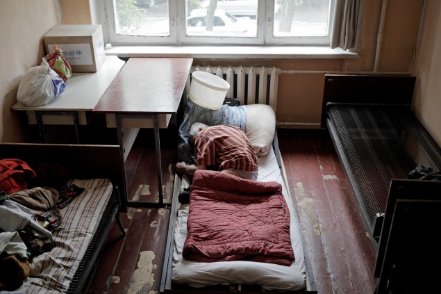 Muž bez nôh leží na podlahe krízovej ubytovne pre ľudí, ktorým ostreľovanie zničilo domy.